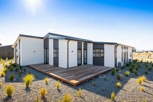 Un bâtiment moderne doté d’un toit plat, de grandes fenêtres et d’une terrasse en bois.