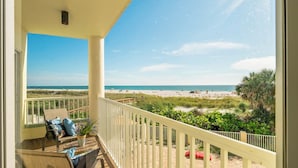 Ein Balkon mit Blick auf einen Strand, einer Holzterrasse und einem Geländer.
