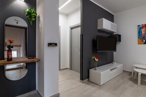 Una sala de estar moderna con un televisor de pantalla plana, una consola de madera y un sofá blanco.