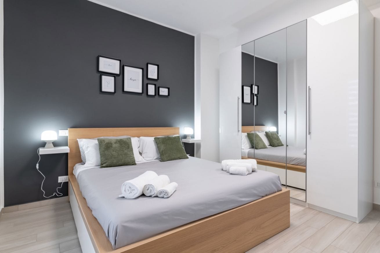 A modern bedroom with a bed, bedside tables, a mirror, and framed pictures on the wall.