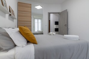 A bedroom with a bed, pillows, a mirror, a door, and a window. - Modern apartment of about 80 square meters, able to comfortably accommodate up to 5 people, located on the third floor of a building with a lift. The property is located in a central position, a few minutes on foot from the famous Massimo and Politeama t (Palermo)