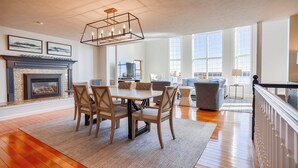 Una sala de estar amplia con chimenea, un comedor y ventanas grandes con vistas.