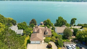 Un barrio residencial con casas cerca de un lago, destacando una vivienda grande con garaje y entrada para vehículos.