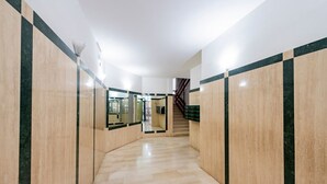 En hall med marmorgolv, en trappa och en glasdörr som leder till ett annat område.