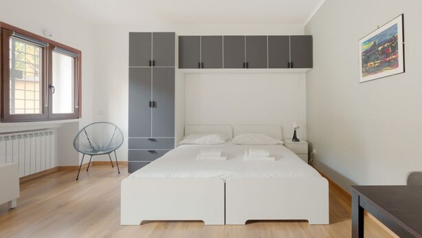 Une chambre à coucher avec un lit, une chaise, un radiateur et une fenêtre.