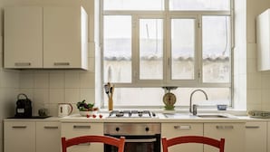 A kitchen with white cabinets, a gas stove, a sink, and a window with a view of the beach.