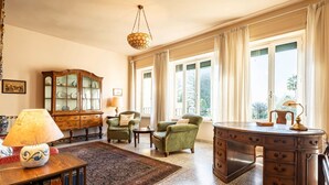 A spacious room with a large desk, two armchairs, a cabinet, and a rug. - GuestHost - In the heart of Taormina, a stunning 140 sqm apartment on the first floor of a building without an elevator. Perfect for 4 guests, it offers spacious interiors and a magnificent terrace with a partial sea view. Located in the city center, it  (Taormina)
