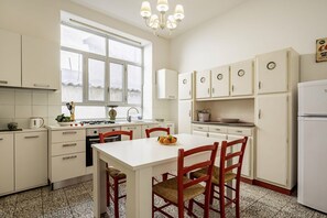 Una cucina con mobili bianchi, un fornello, un lavello e un tavolo da pranzo con sedie.