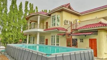 Una casa a due piani con piscina, un balcone e una scala che conduce al piano superiore.