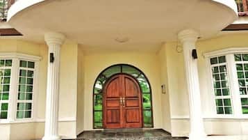 A grand entrance with a large wooden door, flanked by white columns and a semi-circular balcony.