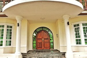 A grand entrance with a large wooden door, flanked by white columns and a semi-circular balcony.