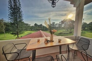 Ein Tisch mit Stühlen auf einem Balkon mit Blick auf einen Golfplatz.