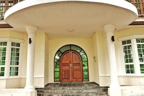 Una entrada imponente con una puerta de madera grande, columnas blancas y un porche cubierto.