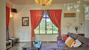 A living room with a sofa, coffee table, and a chandelier. - Yussy Homestay at Afamosa Bungalow (Pegoh)