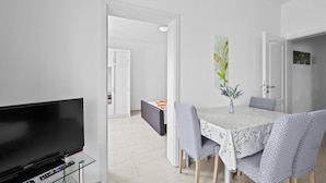 A modern living room with a flat-screen TV, a dining table with chairs, and a kitchen area visible through an open door. - Beautiful apartment in Vodice with WiFi (Vodice)
