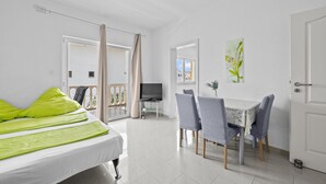 A hotel room with a bed, a dining table with chairs, a television, and a balcony with curtains. - Beautiful apartment in Vodice with WiFi (Vodice)