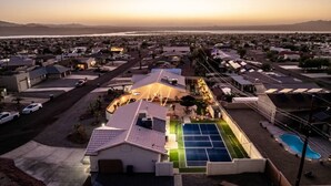 Vue aérienne d’un quartier résidentiel avec des maisons, un court de tennis et une piscine.