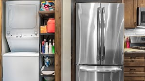 A compact kitchen with a stainless steel refrigerator, a washing machine, and a microwave. - Downtown Whitefish condo centrally located with great views and AC (Whitefish)