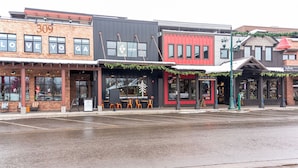 A street view of a row of commercial buildings with storefronts, including a yoga studio and a bar. - Downtown Whitefish condo centrally located with great views and AC (Whitefish)
