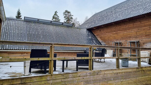 A wooden deck with outdoor seating and a metal roof structure.