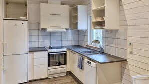 A compact kitchen with white cabinetry, a built-in oven, a dishwasher, and a window above the sink.