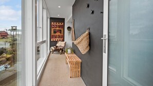 A narrow balcony with a view of a red building, a woven wall hanging, and a wooden bench. - Stunning apartment in Middelfart (Middelfart)