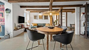 A dining area with a wooden table and black chairs, a hanging light fixture, and a bookshelf with various items. - Stunning apartment in Middelfart (Middelfart)