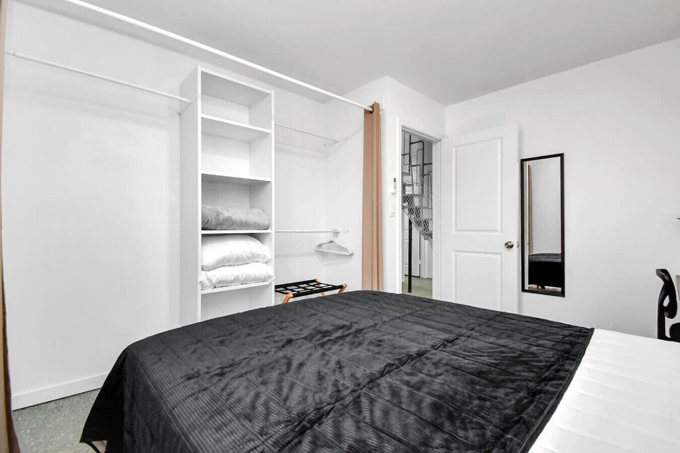 A bedroom with a bed, a wardrobe, and a mirror.