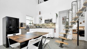 Une cuisine moderne avec un réfrigérateur noir, des armoires blanches et un pare-feu décoré.