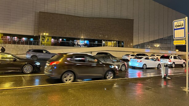 A parking area with multiple cars and a bus stop sign. - World Hostels (Baku)