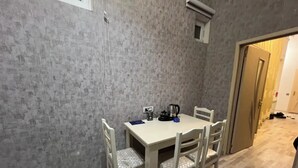 A dining area with a table and four chairs, a kettle, and a small window. - World Hostels (Baku)
