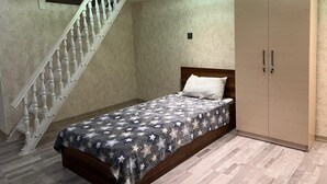 A bedroom with a bed, a wardrobe, and a staircase. - World Hostels (Baku)