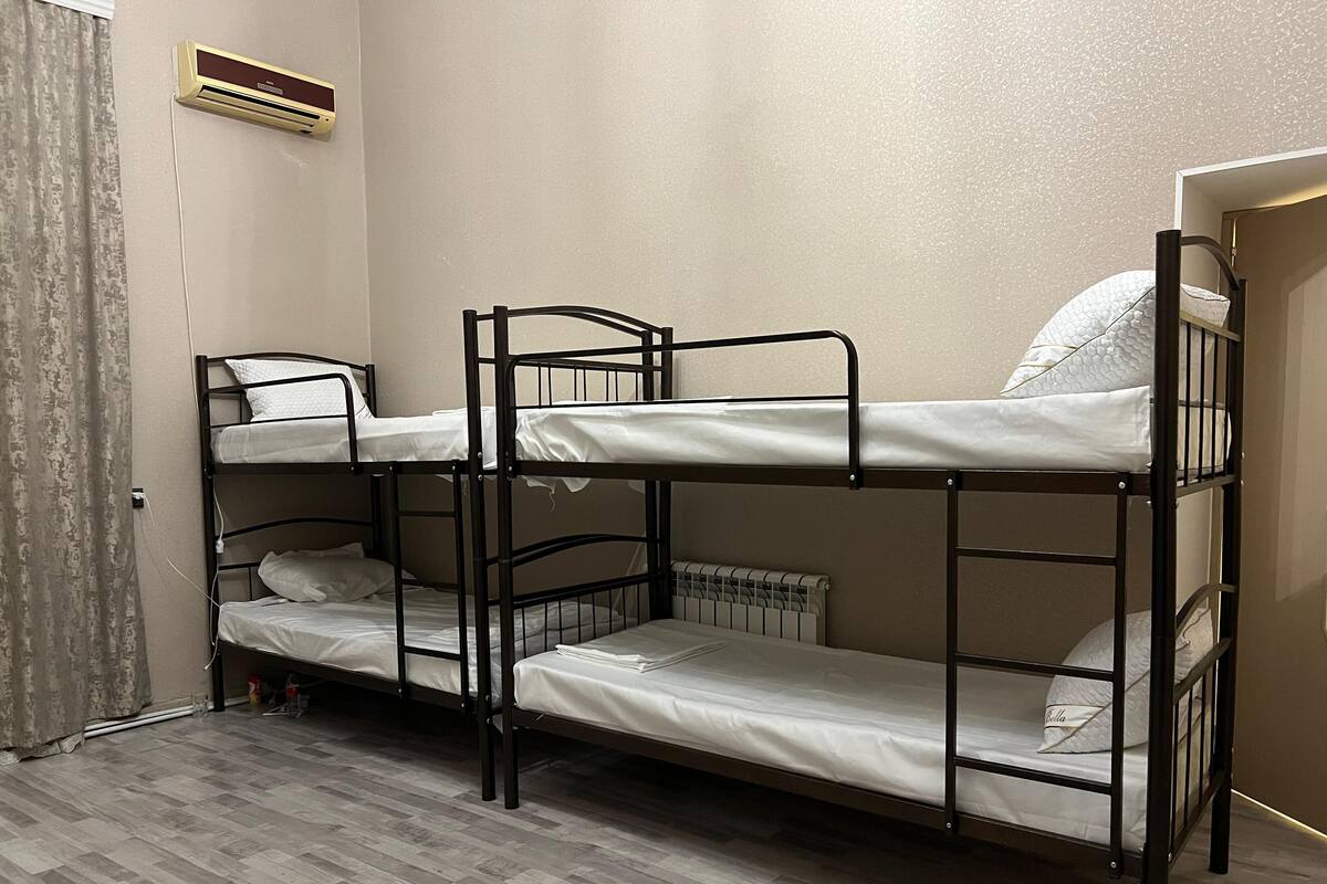 A bunk bed room with a radiator and a power outlet on the wall.