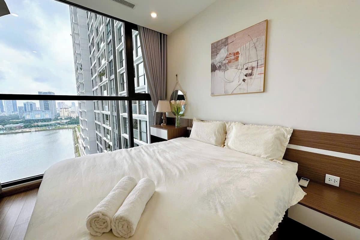 A hotel room with a large bed, a view of a cityscape, and a modern interior design.
