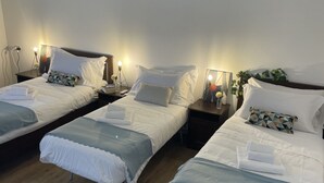 A hotel room with three single beds, each with a pillow and a small bedside table. - Bnbook Trilo Buonarroti Pero (PERO)