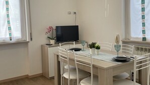 A dining area with a table, chairs, a television, and decorative items. - Bnbook Trilo Buonarroti Pero (PERO)