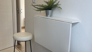A small, white room with a white stool, a white bench, and a potted plant on a white shelf. - Bnbook Trilo Buonarroti Pero (PERO)