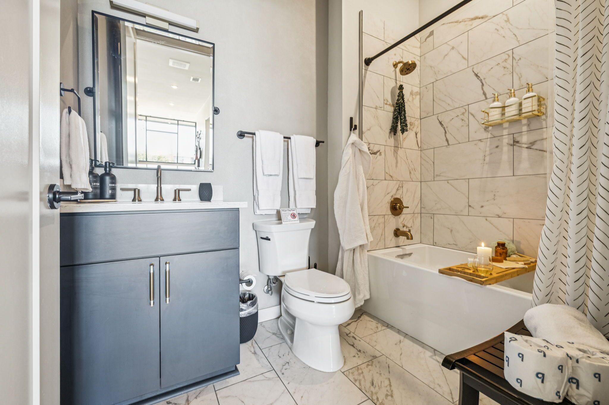 Een moderne badkamer met een marmeren douche, een badkuip en een wastafel met spiegel.