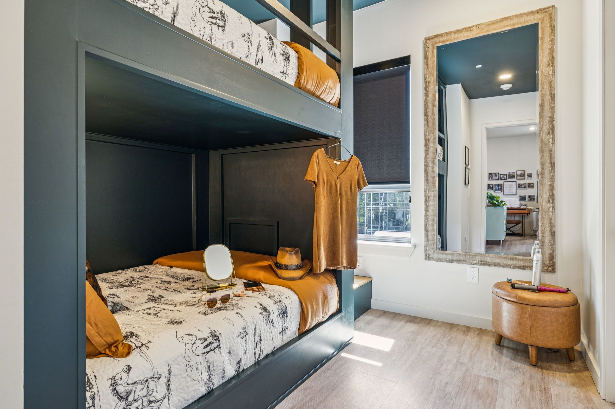 Un dormitorio con una cama litera, una mesita de noche con espejo y un ventanal con vistas.