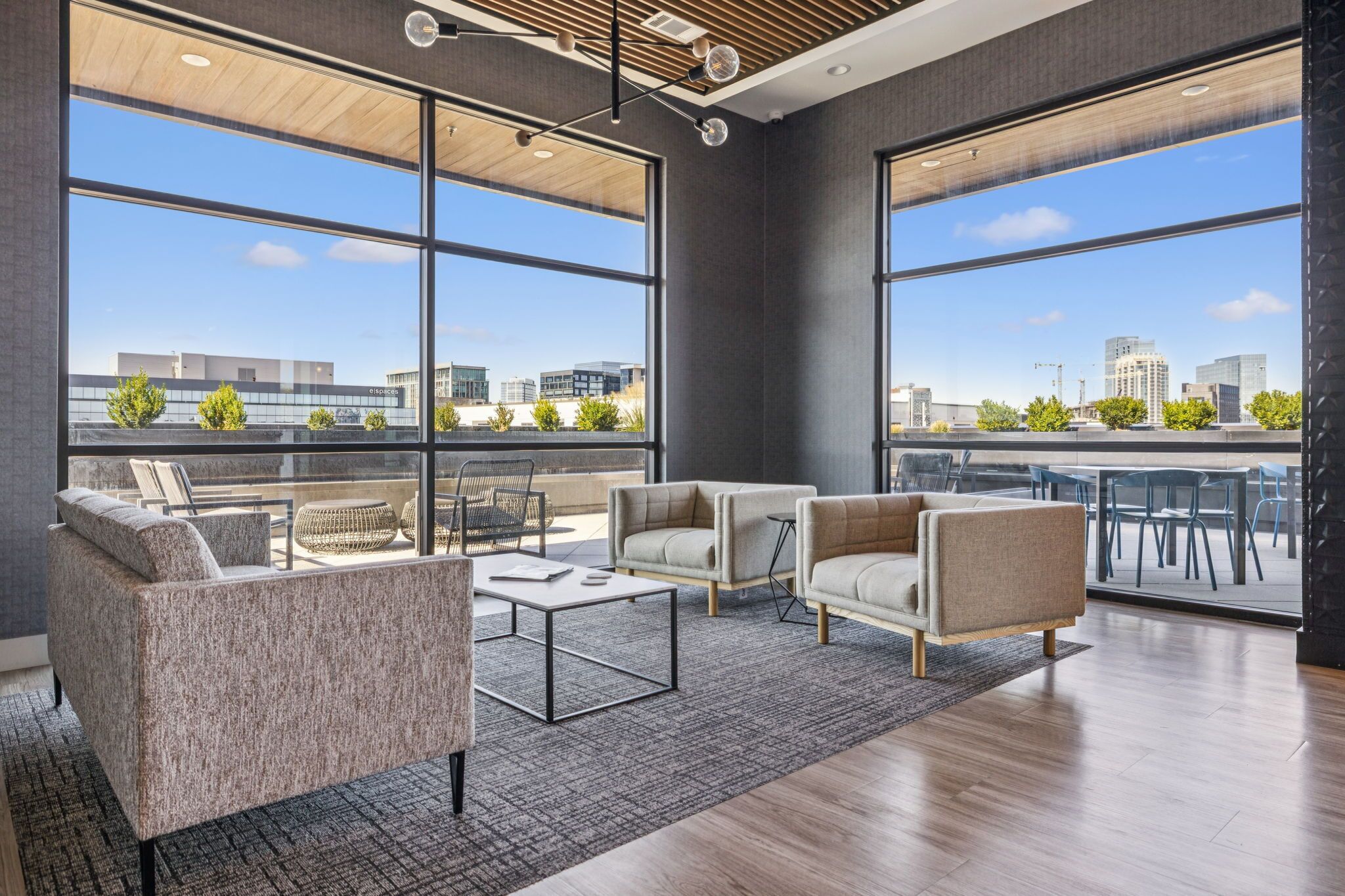 A modern lounge with large windows, comfortable seating, and a city view.