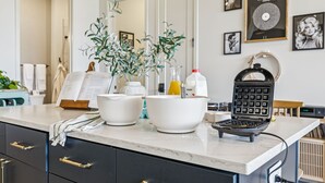 A kitchen counter with white bowls, a waffle maker, and a plant. - H&O on Music Row (Nashville)