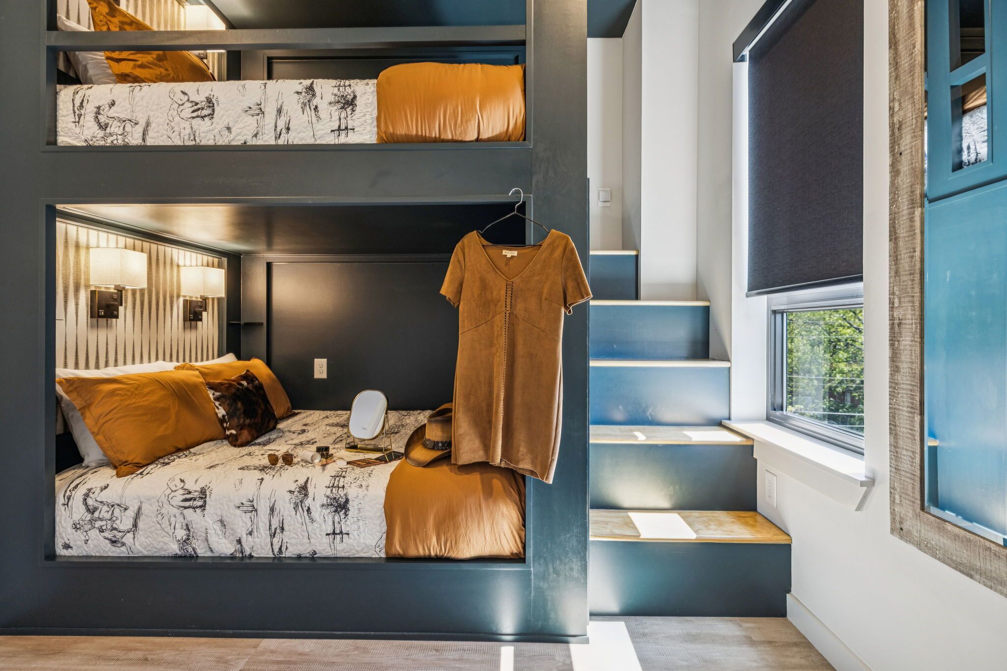A modern bedroom with a bunk bed, a hanging dress, and a view of the outdoors.