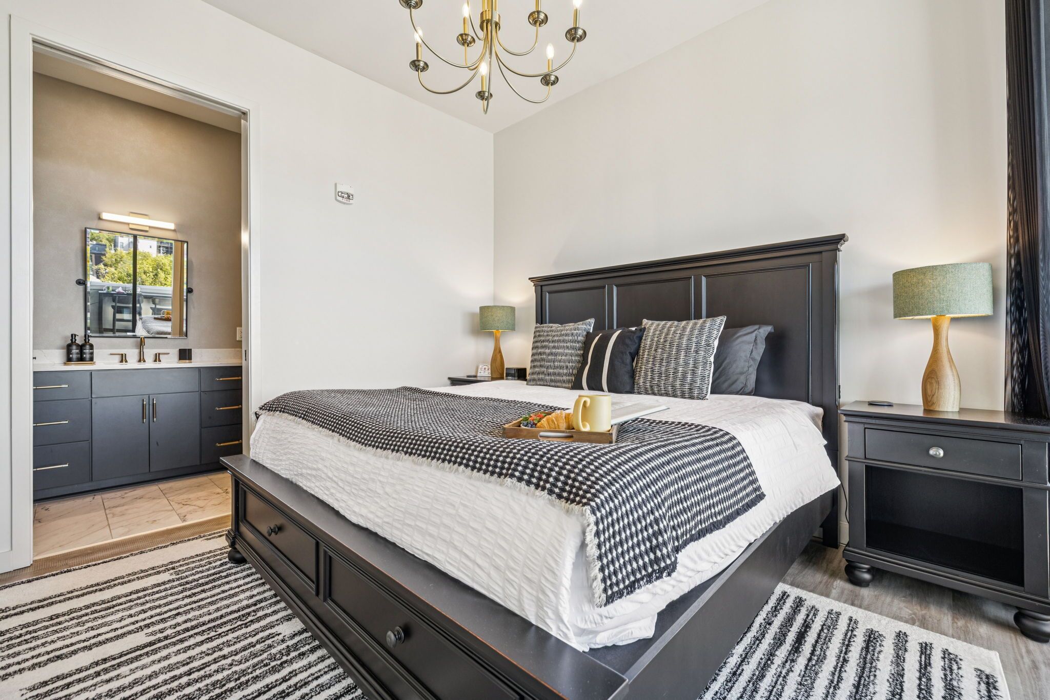 Une chambre à coucher moderne avec un grand lit, une tête de lit en bois foncé, des lampes de chevet et un lustre.