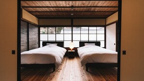 A room with two beds, wooden flooring, and a large window with a view of a traditional building. - RITA Unnan Yoshida (Unnan)
