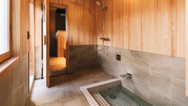 A wooden sauna with a tiled floor, a shower area, and a bench. - RITA Unnan Yoshida (Unnan)