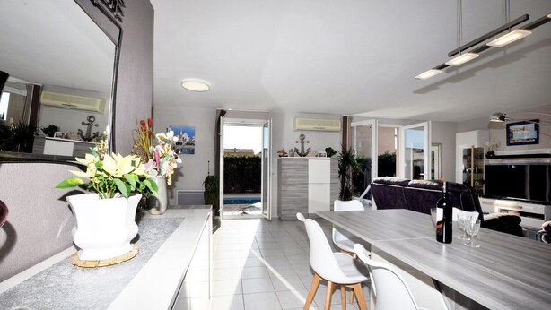A modern kitchen with a dining area, a large TV, and a view of the outdoors. - Lovely home in Lézignan-Corbières (Lézignan-Corbières)