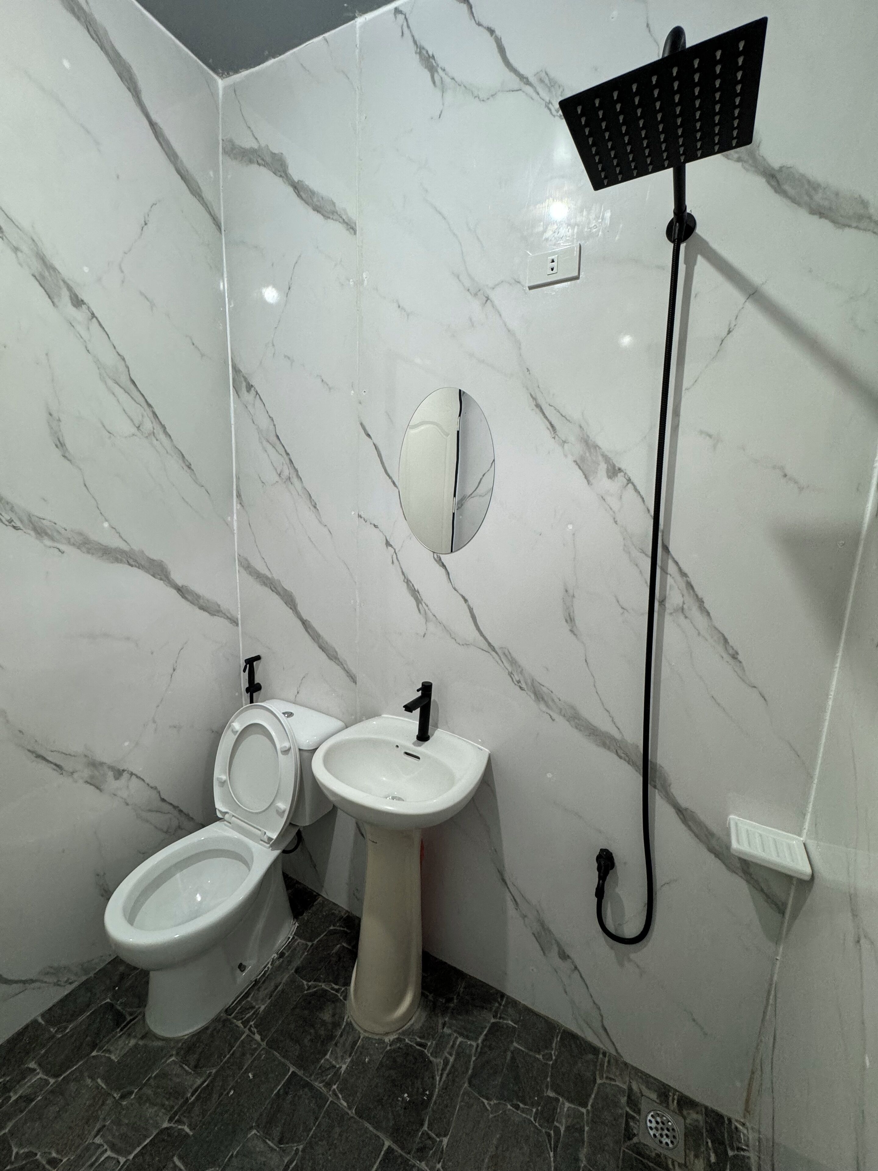 Et badeværelse med toilet, vask og brusebad.