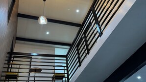 Un interior moderno con una lámpara de techo con forma de estrella, un balcón con barandilla metálica y una escalera.