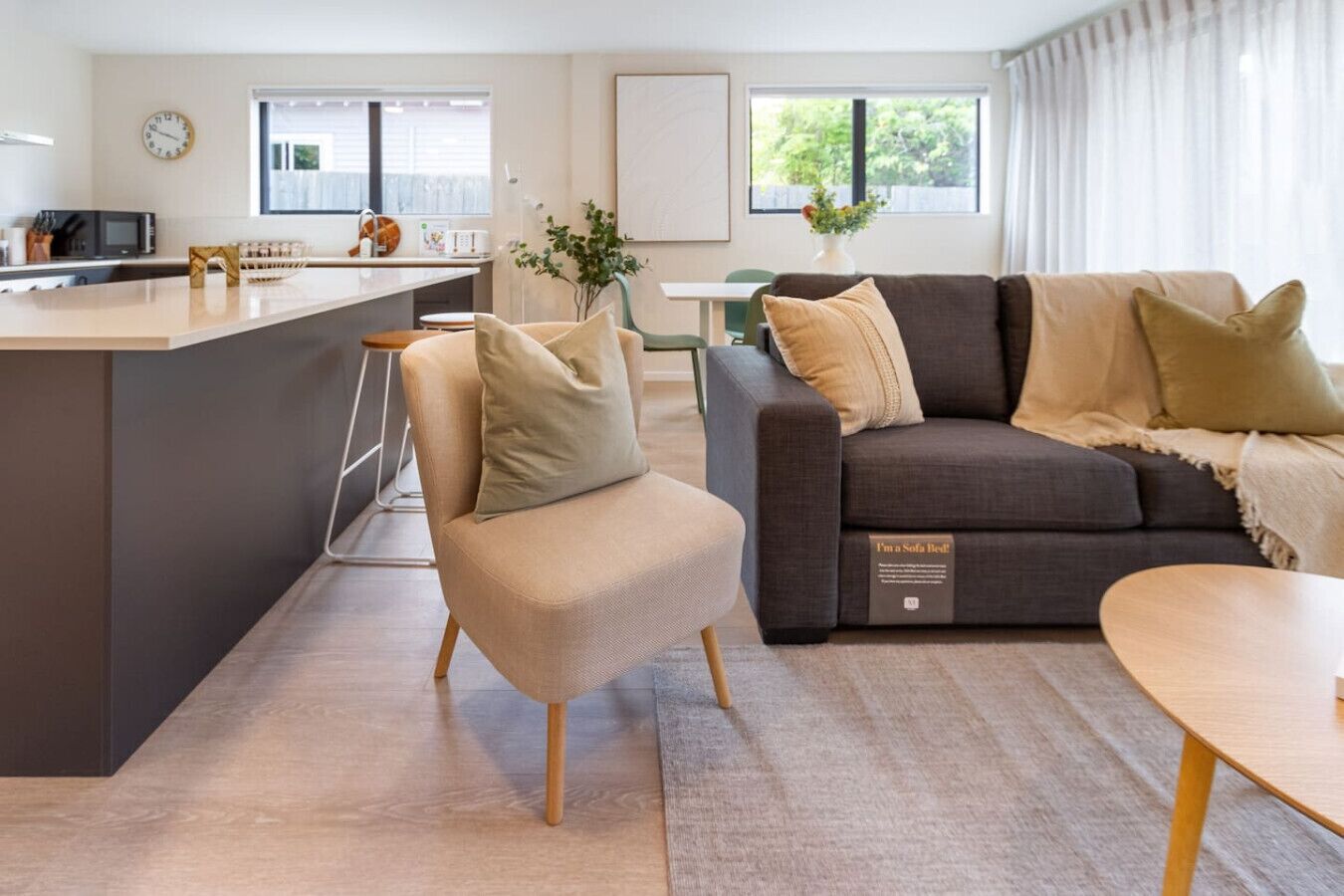 Una sala de estar moderna con sofá cama, comedor y cocina.