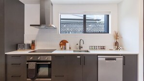 Una cocina moderna con armarios oscuros, horno empotrado, lavavajillas y una ventana sobre el fregadero.